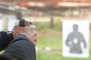 man at an outdoor shooting range aiming a pistol towards a paper target