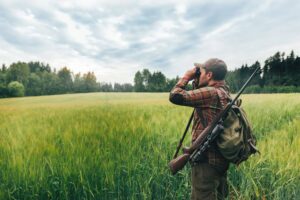 Man carrying a backpack and hunting gear in a field