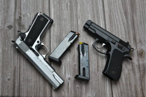 Two pistols and two magazines lying on a wooden table