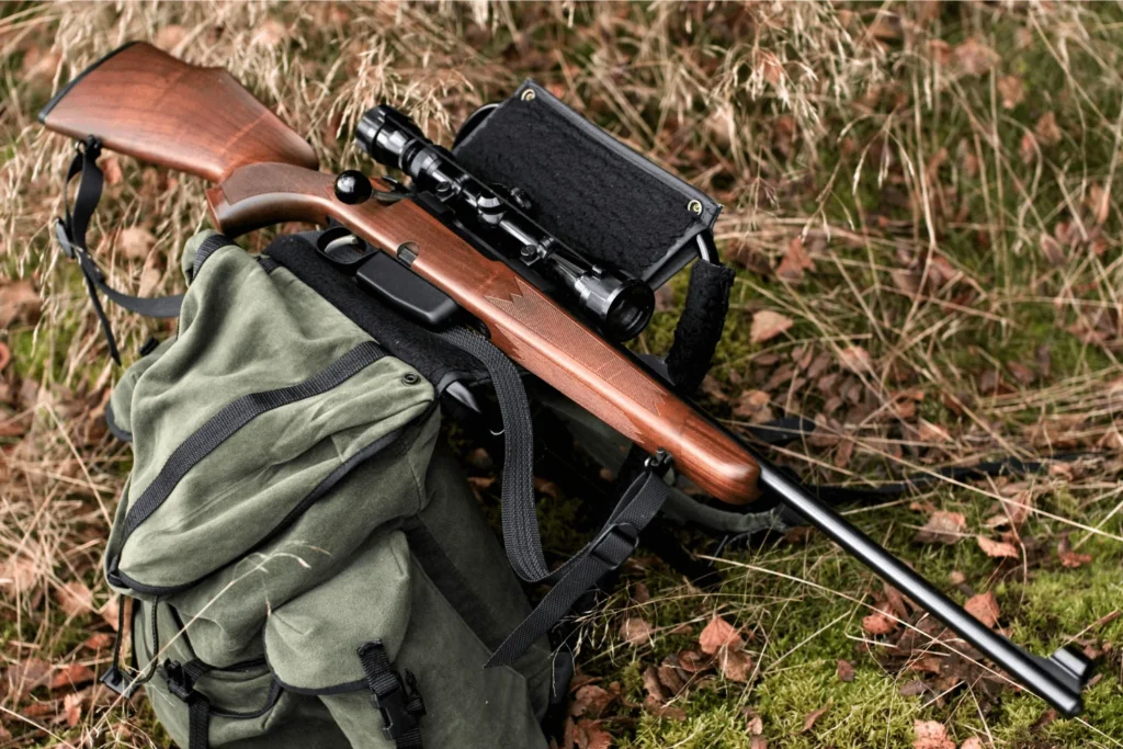 A hunting rifle and tactical carry bag lying in a field