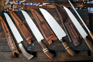 Knives and sheaths laid across a piece of wood