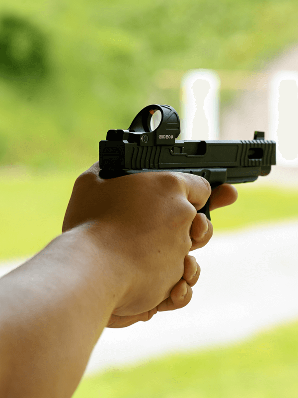 hands gripping a pistol at an outdoor shooting range