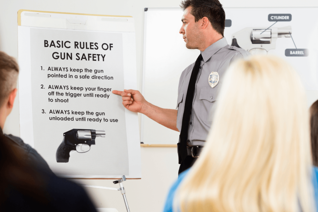 Man in a police uniform instructing a class on basic rules of gun safety
