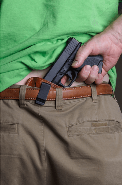Behind the back view of a man pulling his pistol out of his holster