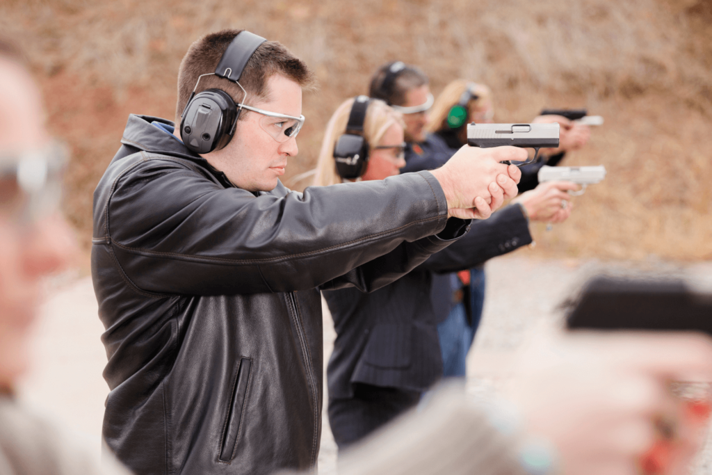 group of people at outdoor shooting range wearing eye and ear protection while firing their guns