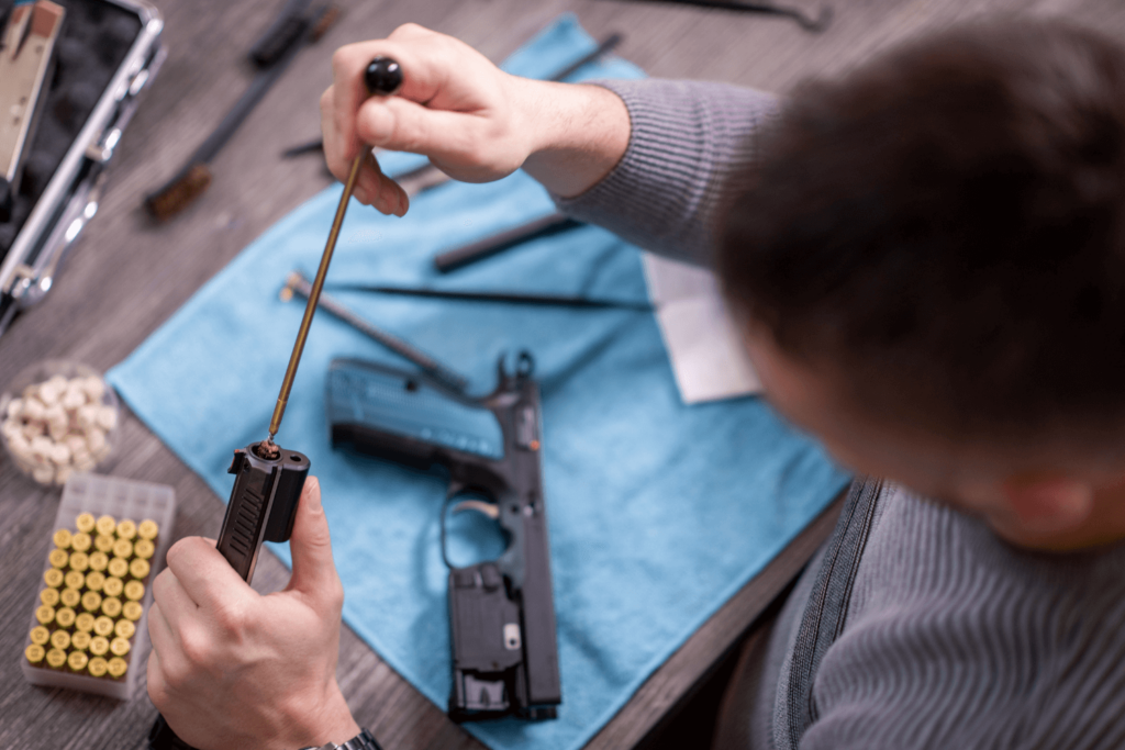 overhead view of man cleaning his pistol with all cleaning supplies on a towel